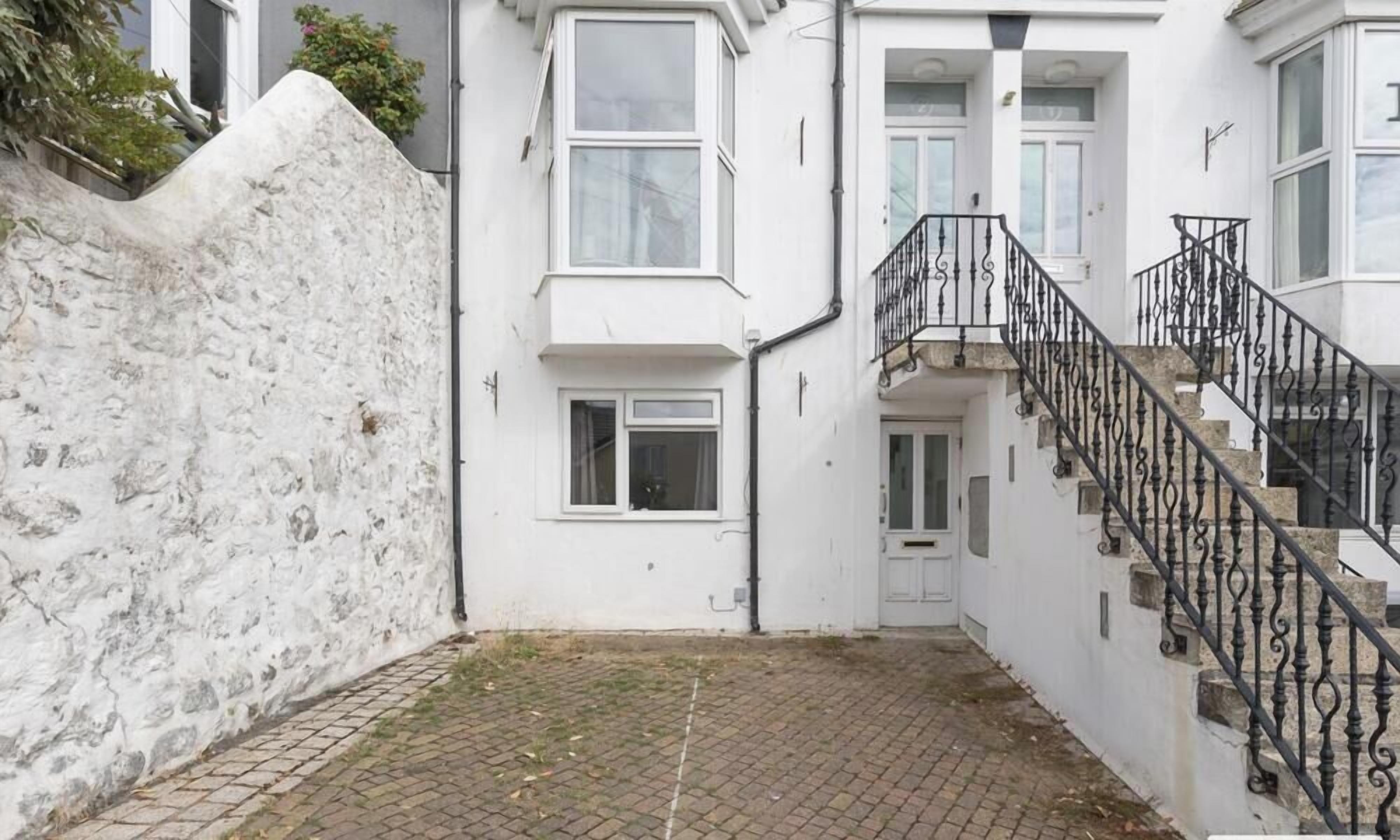 A white building with a staircase and a small door.