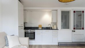 Een compacte keuken met witte kastjes, een inbouwoven en een klein aanrecht.