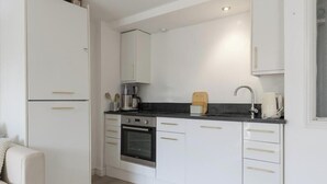 Een compacte keuken met witte kastjes, een zwart aanrechtblad en een inbouwoven.