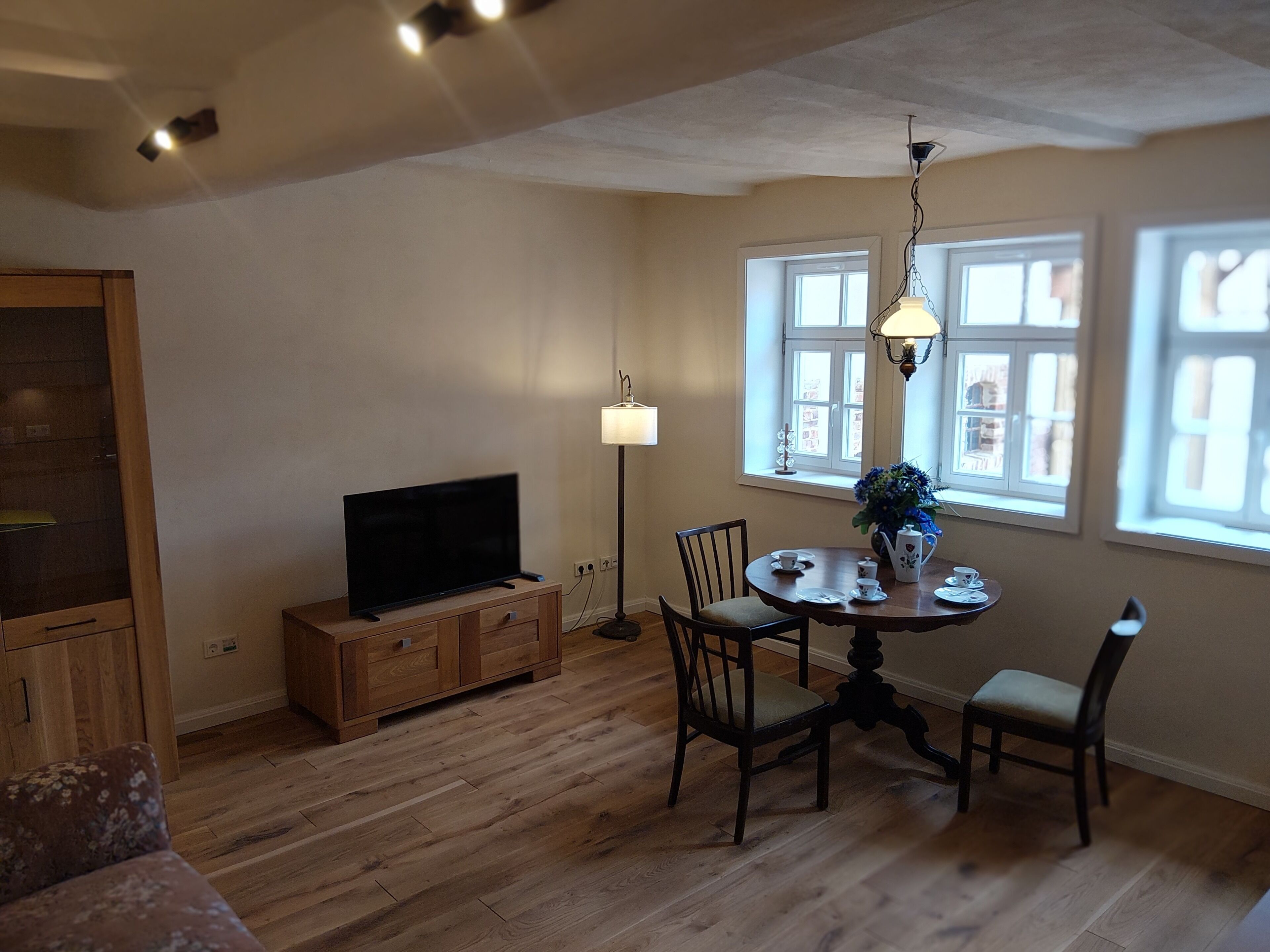 Ein Essbereich mit Tisch, Stühlen, einem Fernseher und einer Lampe.