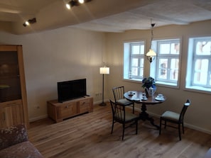A dining area with a table, chairs, a television, and a lamp. - LANDHAUS ELLENBACH - Romantic Half-Timbered Charm on the Fulda River, Cozy Vacation Rental in a Historic Building (Alheim)