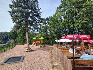 A park with wooden benches, a playground, and red umbrellas. - LANDHAUS ELLENBACH - Romantic Half-Timbered Charm on the Fulda River, Cozy Vacation Rental in a Historic Building (Alheim)