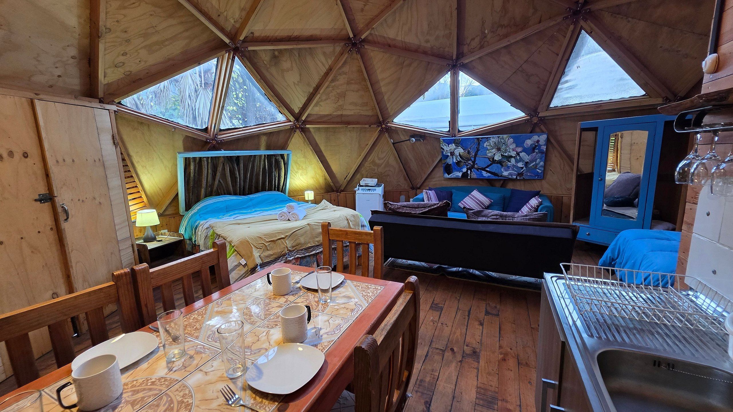 Een gezellig interieur met een bed, een zithoek en een eettafel gedekt voor twee personen.
