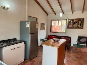 A compact kitchen with a gas stove, a stainless steel refrigerator, and a wooden island.