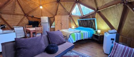 A tent with a bed, a sofa, a table, and a television.