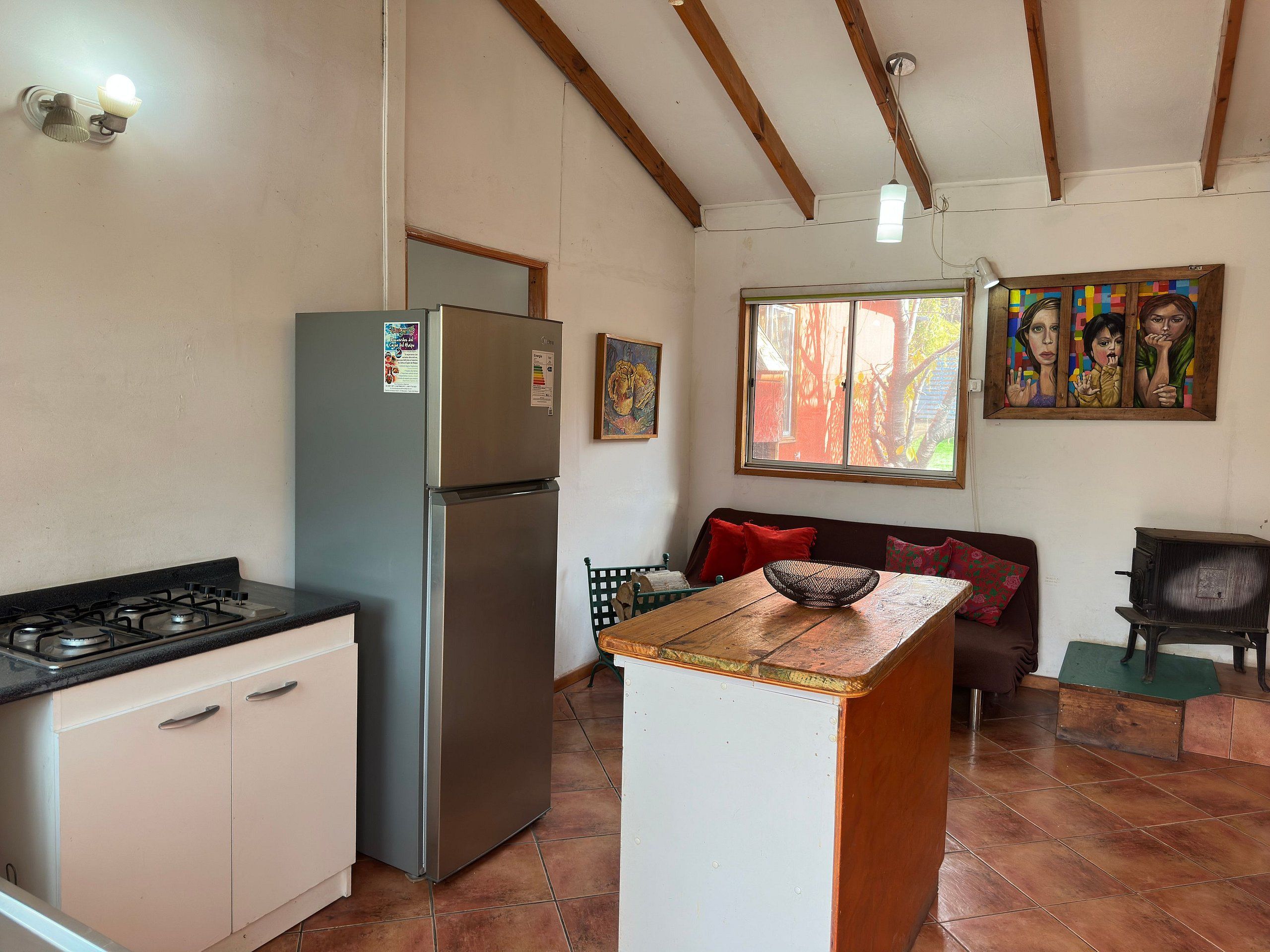 A compact kitchen with a gas stove, a stainless steel refrigerator, and a wooden island.