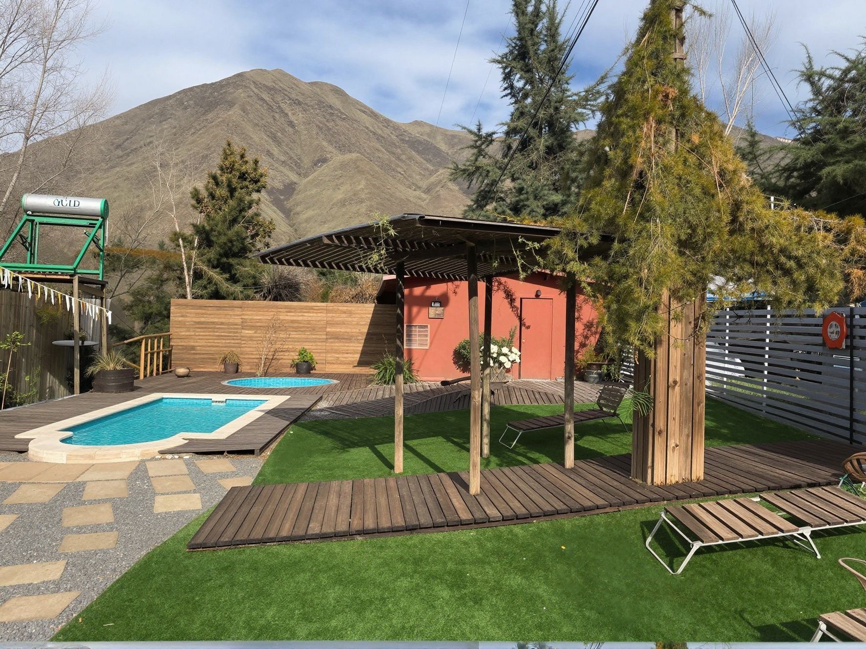 Un jardin avec une piscine, une terrasse en bois et une pergola.