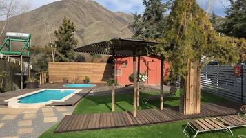 Un jardin avec une piscine, une terrasse en bois et une pergola.