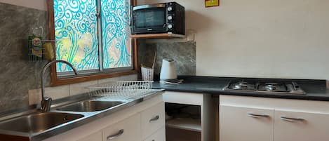 Une cuisine équipée d’un four à micro-ondes, d’un évier et de placards.