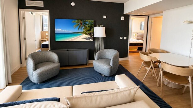 A modern living room with a large flat-screen TV, two armchairs, a sofa, a dining table with chairs, and a floor lamp. - 2 Bedrooms Condo with Balcony & Amazing Views in Downtown (Miami)