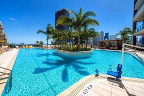 A swimming pool with a palm tree planter, a lifeguard stand, and a city skyline in the background. - 2 Bedrooms Condo with Balcony & Amazing Views in Downtown (Miami)