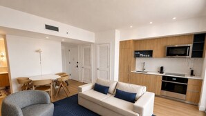 A modern living room with a sofa, armchair, and dining table. - 2 Bedrooms Condo with Balcony & Amazing Views in Downtown (Miami)