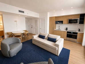 A modern living room with a sofa, armchair, and dining table. - 2 Bedrooms Condo with Balcony & Amazing Views in Downtown (Miami)