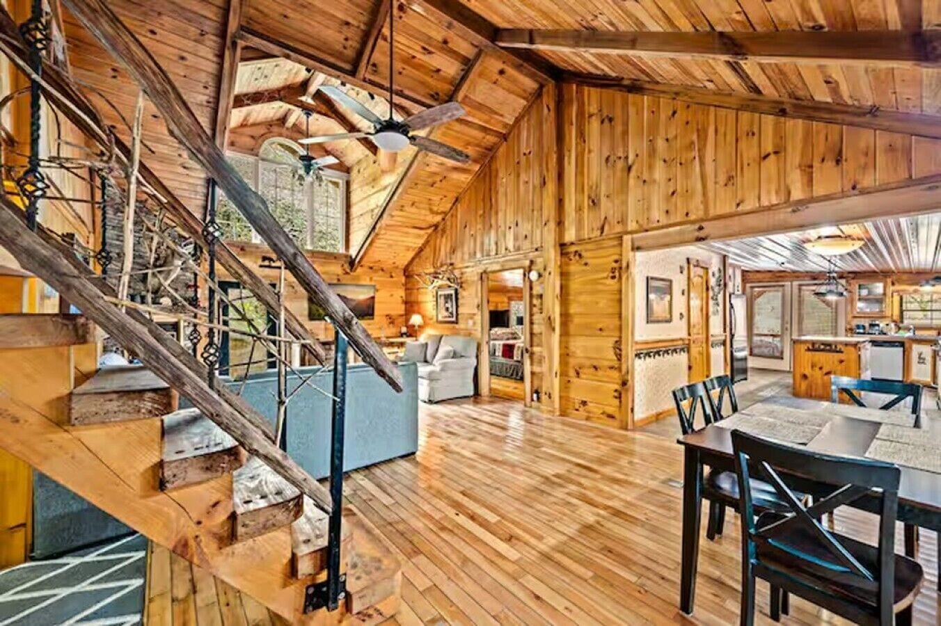 A spacious wooden interior with a staircase, a dining area, and a kitchen.
