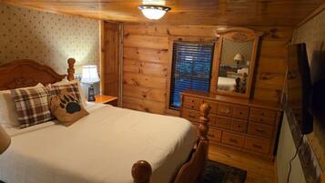 Quarto de cabana de madeira com cama, mesa de cabeceira, cômoda e espelho.