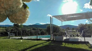 A pool area with a view of mountains, a covered seating area, and a fenced garden. - Wellness Retreat between Marche and Umbria (Sassoferrato)