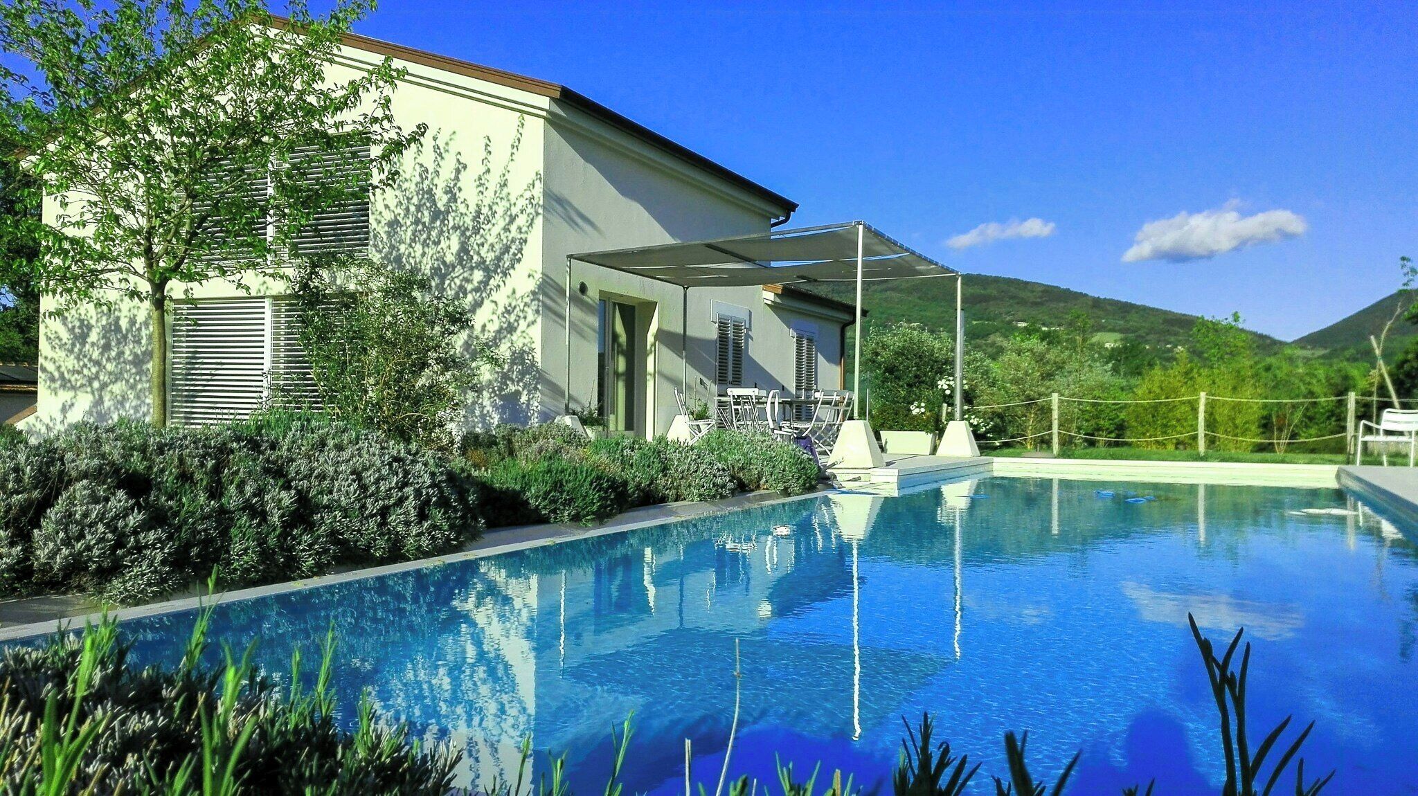 Une piscine avec une maison et des montagnes en arrière-plan.