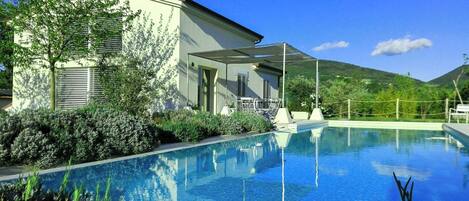 Ein Schwimmbad mit einem Haus und Bergen im Hintergrund.
