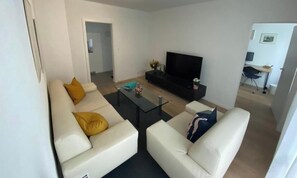 Ein modernes Wohnzimmer mit einer Sofagarnitur, einem Couchtisch und einem Flachbildfernseher.