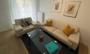Ein modernes Wohnzimmer mit zwei Sofas, einem Couchtisch und Kunstwerken an der Wand.