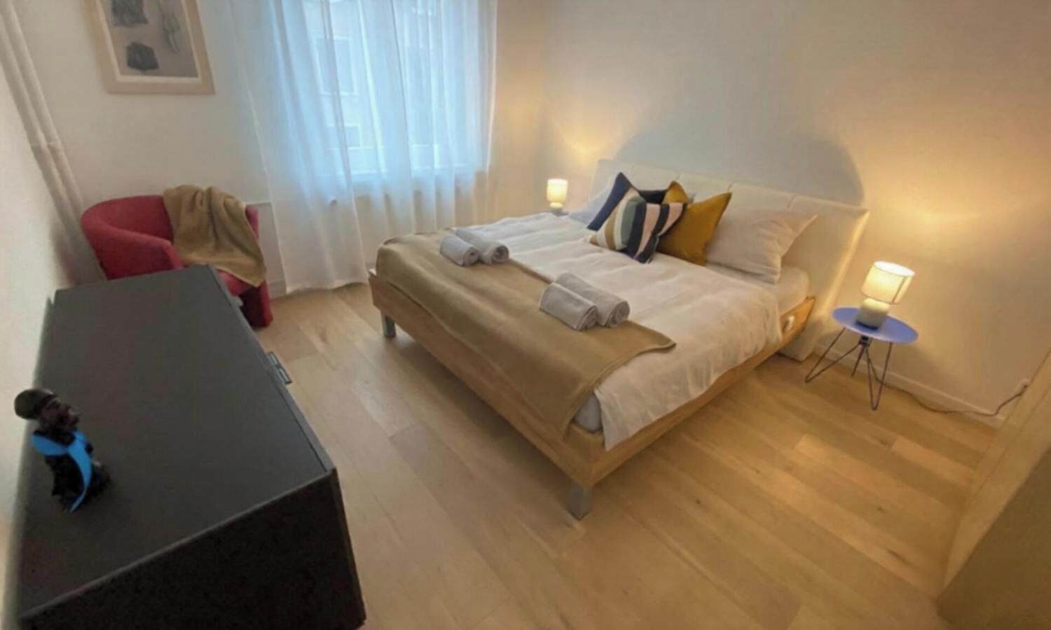 Une chambre d’hôtel comprenant un lit, une table de chevet, une lampe et une petite table avec une chaise.