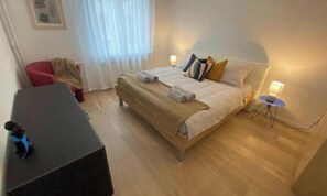 Une chambre d’hôtel comprenant un lit, une table de chevet, une lampe et une petite table avec une chaise.