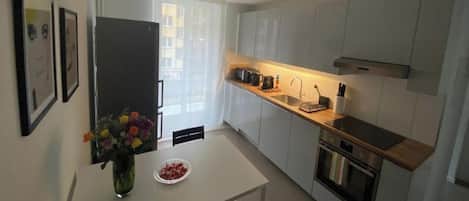 A modern kitchen with white cabinets, a wooden countertop, and a built-in oven.
