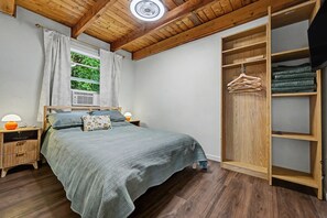 A bedroom with a bed, bedside tables, a wardrobe, and a window with curtains. - NEW GreenHouse at the Lake (Tobyhanna)