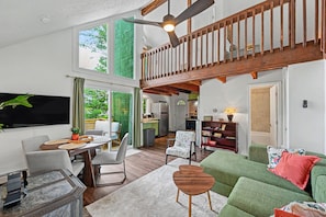 A spacious living area with a dining table, chairs, a sofa, and a television. - NEW GreenHouse at the Lake (Tobyhanna)