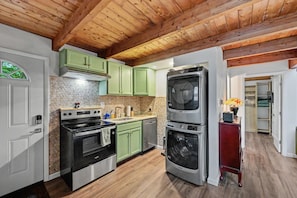 A kitchen with wooden beams, green cabinets, a stove, oven, and a washing machine. - NEW GreenHouse at the Lake (Tobyhanna)