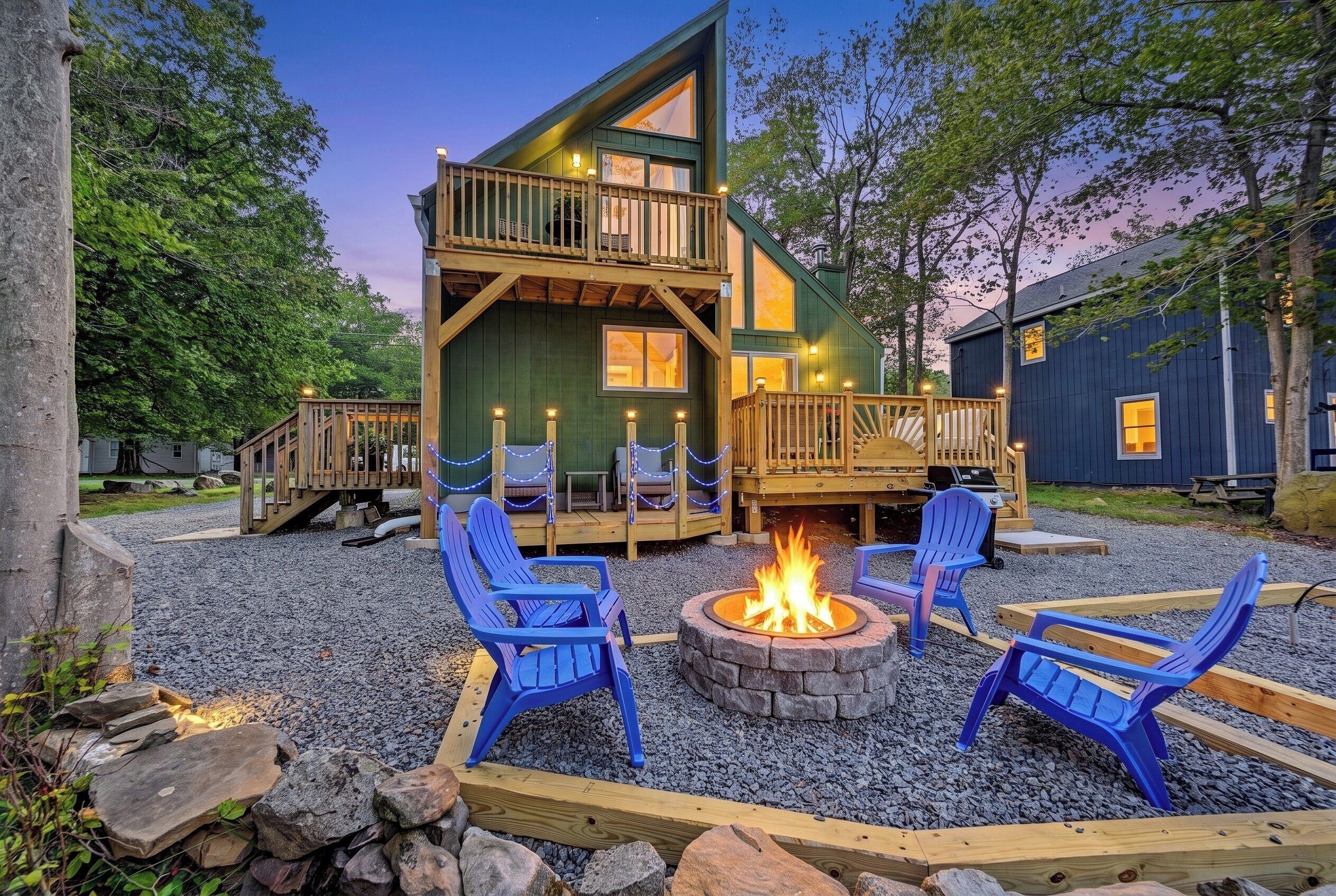 Une cabane à deux étages avec une terrasse, un espace salon extérieur et un foyer.