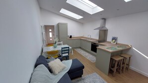 Ett kompakt bostadsutrymme med ett litet kök, en matplats och en soffa.