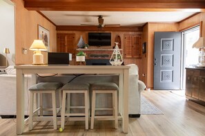 A kitchen with a wooden ceiling, a built-in stove, and a dining area with a table and two chairs. - Flossie's and Maudie's Lake Retreat (Lyon Township)