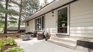 Een woonhuis met een overdekte veranda, buiten zitplaatsen en een vuurkorf.