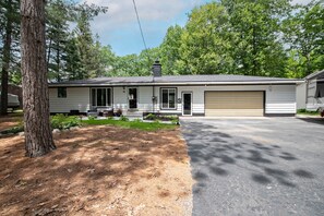 A single-story house with a garage, a front porch, and a well-maintained lawn. - Flossie's and Maudie's Lake Retreat (Lyon Township)