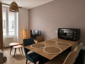 Een moderne eetruimte met een houten tafel, vier stoelen, een televisie en een magnetron.