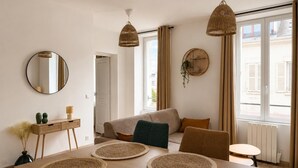 Ein modernes Wohnzimmer mit Esstisch, Sofa und zwei hängenden Korbstühlen.