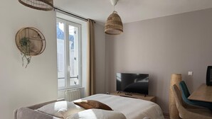 Quarto moderno com cama, TV e área de refeições.