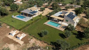 Un quartier résidentiel comprenant deux maisons dotées de piscines, de panneaux solaires et d’une pelouse bien entretenue.