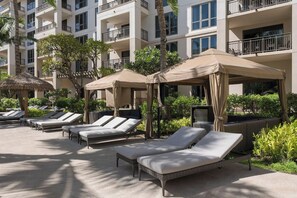 A hotel pool area with sun loungers, umbrellas, and a building with balconies. - 3 Bedroom Villa at Westin Nanea Ocean Resort (Lahaina)