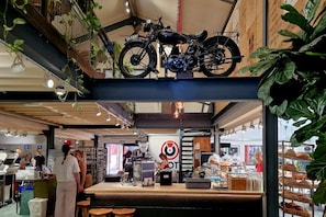 A café with a counter, seating area, and a motorcycle displayed above.