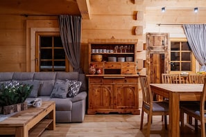 A cozy cabin interior with a sofa, wooden cabinet, and dining table. - A Large Mountain-style House With a spa Area (Poronin)