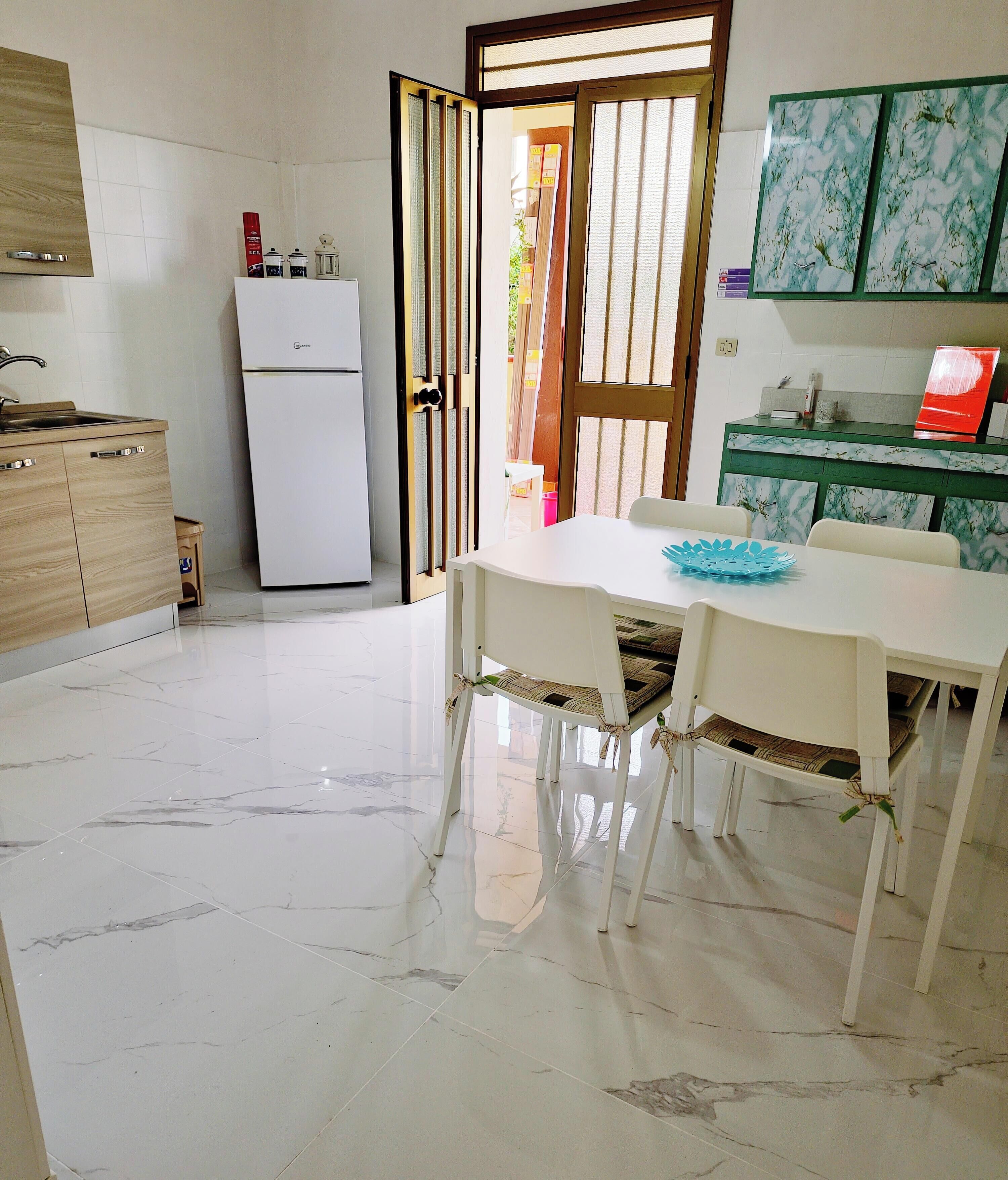 A modern kitchen with a refrigerator, a sink, and a dining table with chairs.