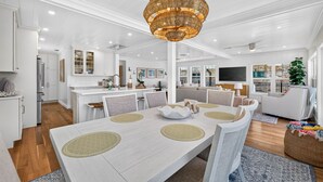 A spacious dining area with a large table, chairs, and a decorative chandelier. - Sandcastle Villa 3BR Beachfront Home (Clearwater Beach)
