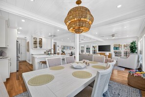A spacious dining area with a large table, chairs, and a decorative chandelier. - Sandcastle Villa 3BR Beachfront Home (Clearwater Beach)