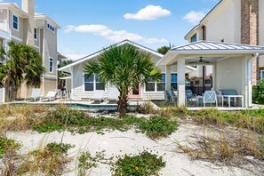 Een strandhuis met zwembad, terras en overdekte patio.