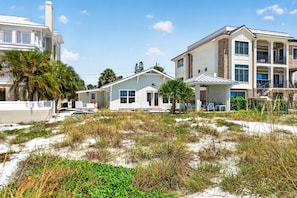 A beachfront property with a two-story building, a covered patio, and a sandy landscape. - Sandcastle Villa offered by Beach Time Rentals (Clearwater Beach)