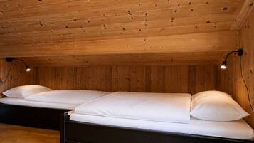 A room with two beds, wooden walls, and a sloped ceiling.