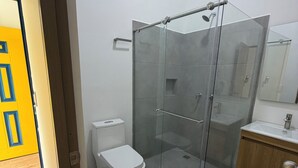 A bathroom with a glass-enclosed shower, a toilet, and a sink with a mirror above it. - salento river hotel (Salento)