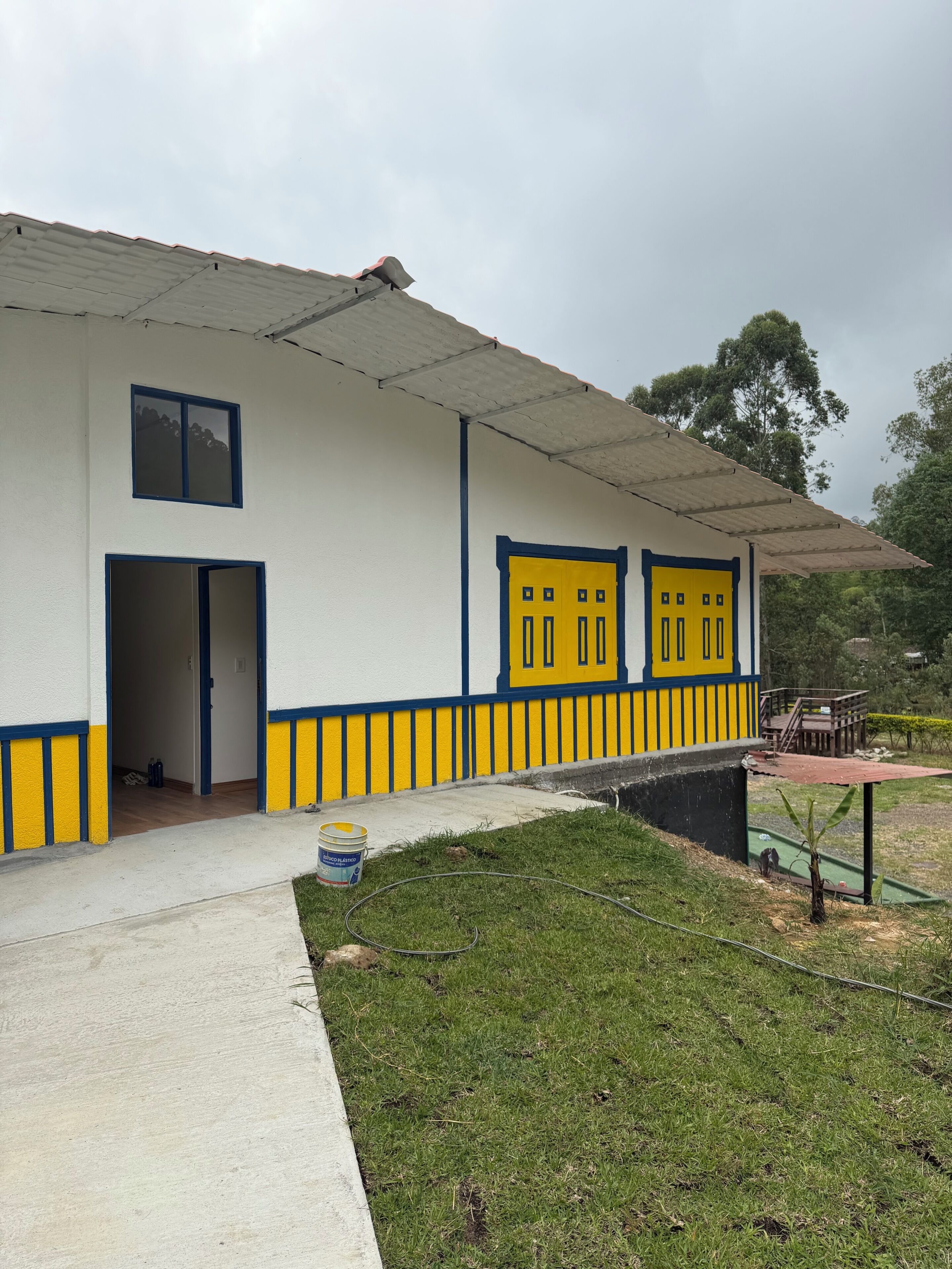 Un edificio con fachada blanca y detalles en amarillo, que cuenta con una puerta y ventanas.